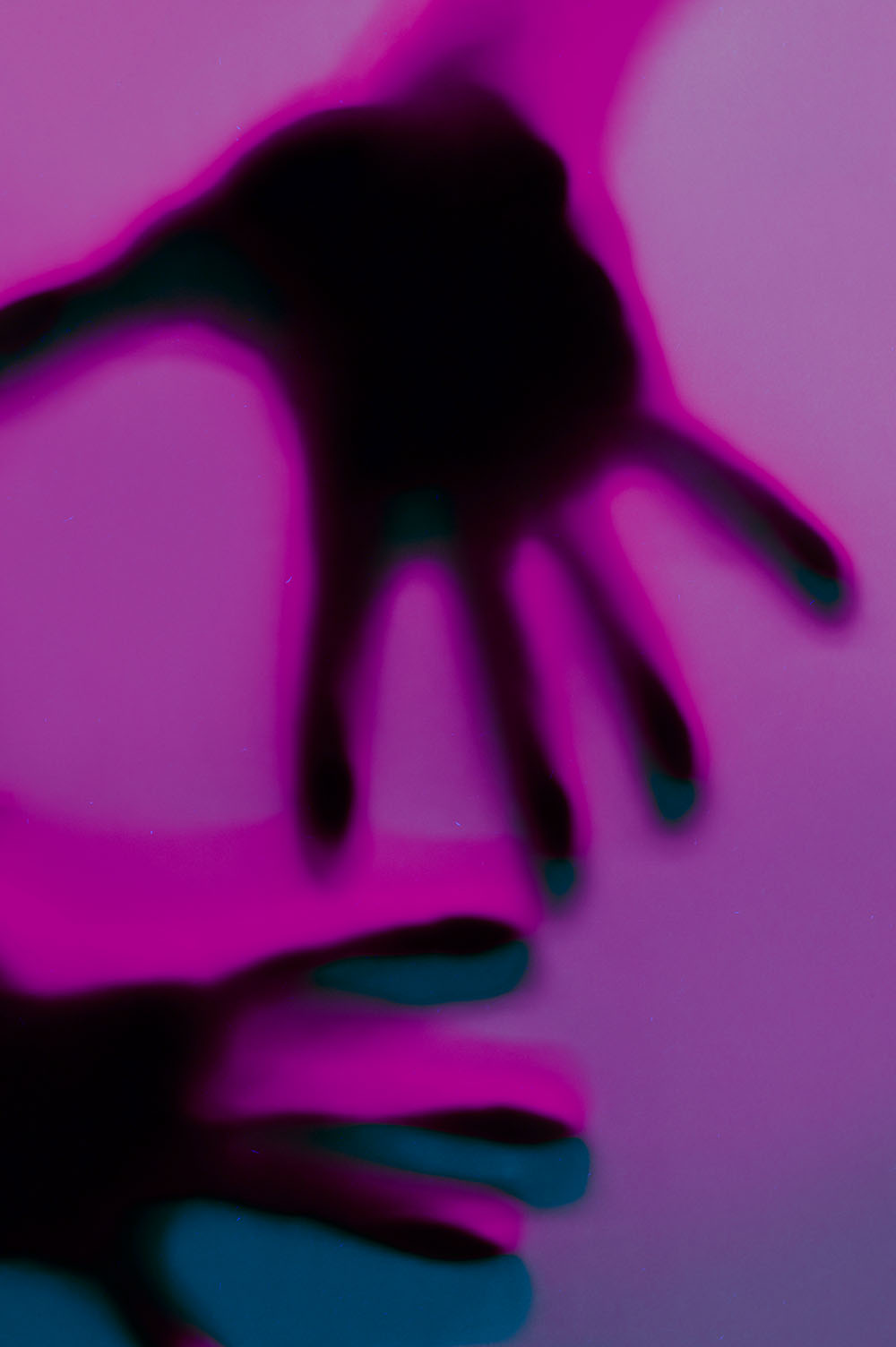 Hands in orange and green neon light gradient behind white surface. Foggy blurred effect for different concept ideas.