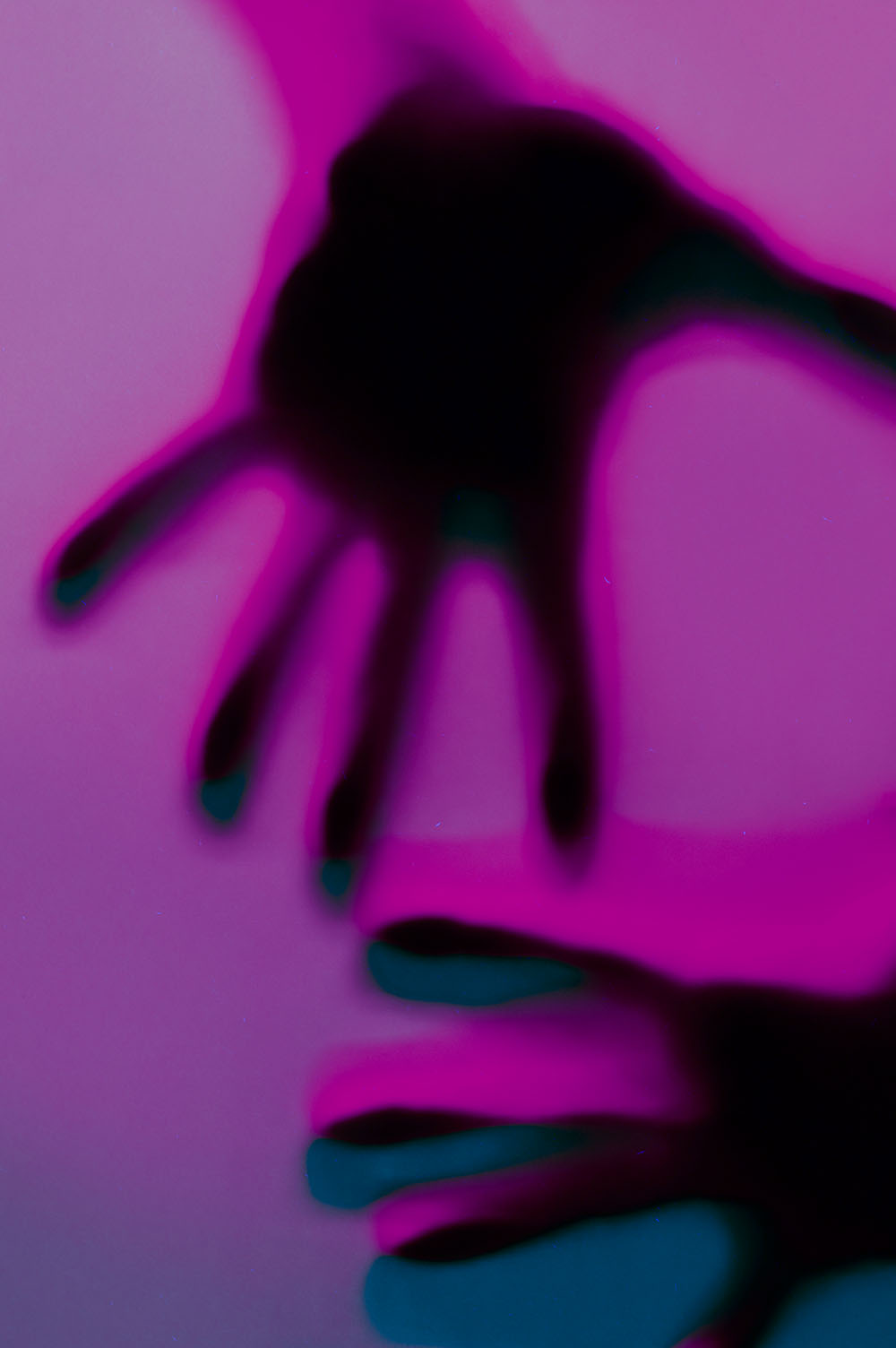 Hands in orange and green neon light gradient behind white surface. Foggy blurred effect for different concept ideas.
