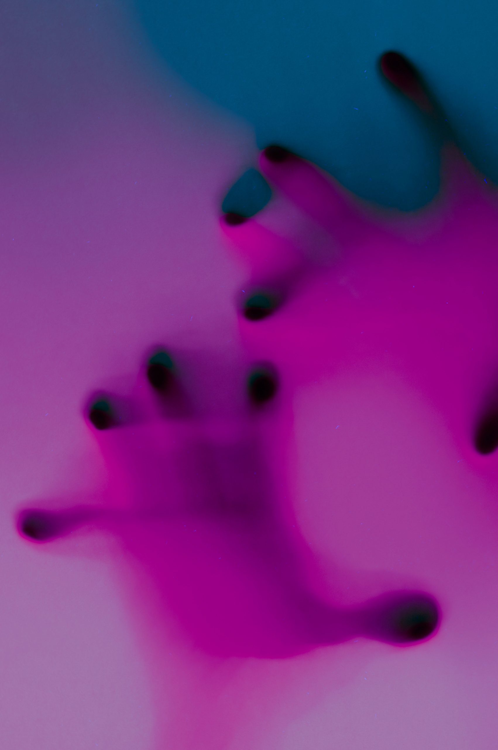 Hands in orange and green neon light gradient behind white surface. Foggy blurred effect for different concept ideas.